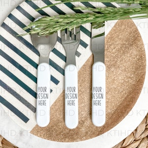 May include: A white plate with black stripes and a brown section in the center. Three silver utensils are placed on the plate. The utensils have white handles with the text "Your Design Here" printed on them.