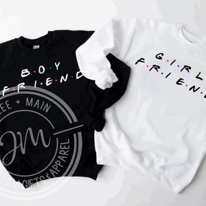 May include: Two black and white sweatshirts with the words "Boyfriend" and "Girlfriend" in colourful letters. The sweatshirts are a matching set.