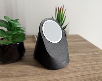 May include: A black wireless charging stand with a white circular charging pad. The stand is on a wooden surface.