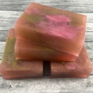 May include: Four bars of handmade soap with a pink and gold swirl pattern. The soap is stacked on top of each other.