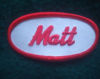 Matt A black work shirt patch that says Matt in white print