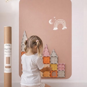 Könnte beinhalten: Ein Kind spielt mit magnetischen Bausteinen auf einer Wandaufkleber in Mokkabraun. Der Wandaufkleber zeigt eine weiße Zeichnung eines Regenbogens und eines Mondes. Eine Rolle des MagicWall-Aufklebers ist links zu sehen. Das Wort "Play" steht auf einem weißen Wimpel.