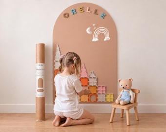 May include: A large arched wall decal in a solid tan color featuring the name ORELLE in colorful letters at the top and a white line drawing of a rainbow and moon. A cardboard shipping tube labeled Orelle MagicWall stands nearby.