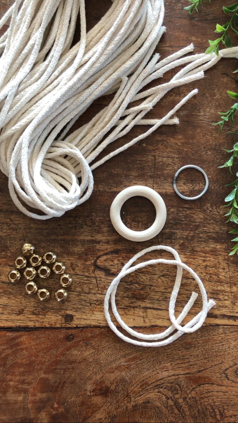 May include: A collection of crafting supplies including white cotton rope, wooden rings, gold beads, and a metal ring.
