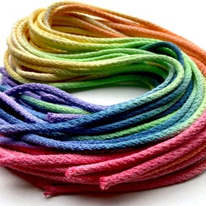 Könnte beinhalten: Nahaufnahme eines regenbogenfarbenen Baumwollkordels mit Ombre-Effekt. Der Kordel besteht aus mehreren Baumwollfäden, die in einem Farbverlauf von Rot über Orange, Gelb, Grün, Blau bis Violett gefärbt wurden.