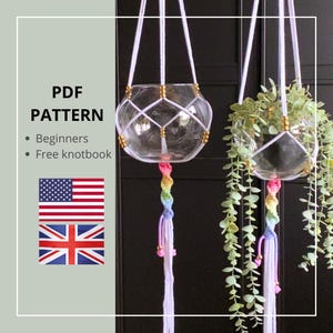 Op de afbeelding: Twee glazen hangplanten met wit macramé net en regenboogkwasten. Eén plantenbak bevat groen. De afbeelding bevat de tekst "PDF PATTERN" en de vlaggen van de Verenigde Staten en het Verenigd Koninkrijk.
