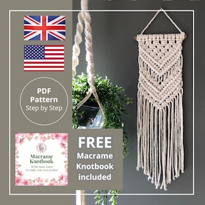 May include: A cream-colored macrame wall hanging with a geometric design, hanging on a gray wall. The image also shows a hanging plant and a graphic with the text "FREE Macrame Knotbook included".