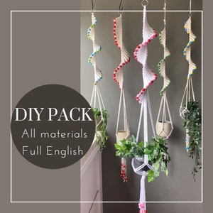 Op de afbeelding: Vijf DIY macramé plantenhangers met kleurrijke kralen. Elke hanger is gemaakt van wit katoenen koord en heeft een spiraalvormig ontwerp. De tekst "DIY PACK All materials Full English" is zichtbaar in de afbeelding.