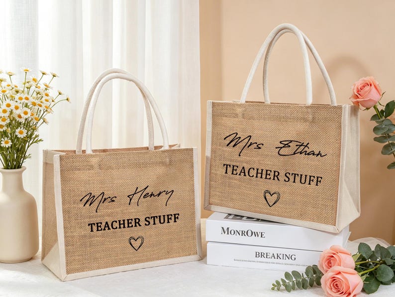 Pu&ograve; includere: Due borse rettangolari in juta con bordi e manici in tessuto bianco. Ogni borsa presenta una scritta nera "Mrs Henry" o "Mrs Ethan" sopra le parole "TEACHER STUFF" e un piccolo cuore disegnato a mano nella parte inferiore.