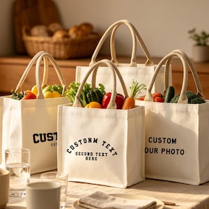 Può includere: Quattro borse tote in tela color crema con manici beige, piene di verdure fresche. Ogni borsa ha testo nero: "CUSTOM EST", "CUSTOM TEXT SECOND TEXT HERE" e "CUSTOM OUR PHOTO". Una tazza e bicchieri in primo piano.