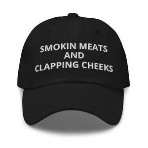 May include: Black baseball cap with white embroidered text that reads "Smokin Meats and Clapping Cheeks".