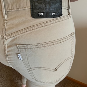 May include: Khaki-colored Levi's 559 jeans. The back pocket features the Levi's logo tag. The leather patch displays the Levi Strauss & Co. logo and the size is 30x32 inches.
