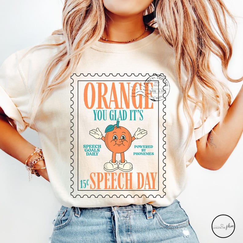 Puede incluir: Camiseta color crema con un dise&ntilde;o de sello postal. El sello dice "ORANGE YOU GLAD IT'S SPEECH DAY" y presenta un personaje de naranja de dibujos animados. El texto incluye "SPEECH GOALS DAILY" y "POWERED BY PHONEMES."