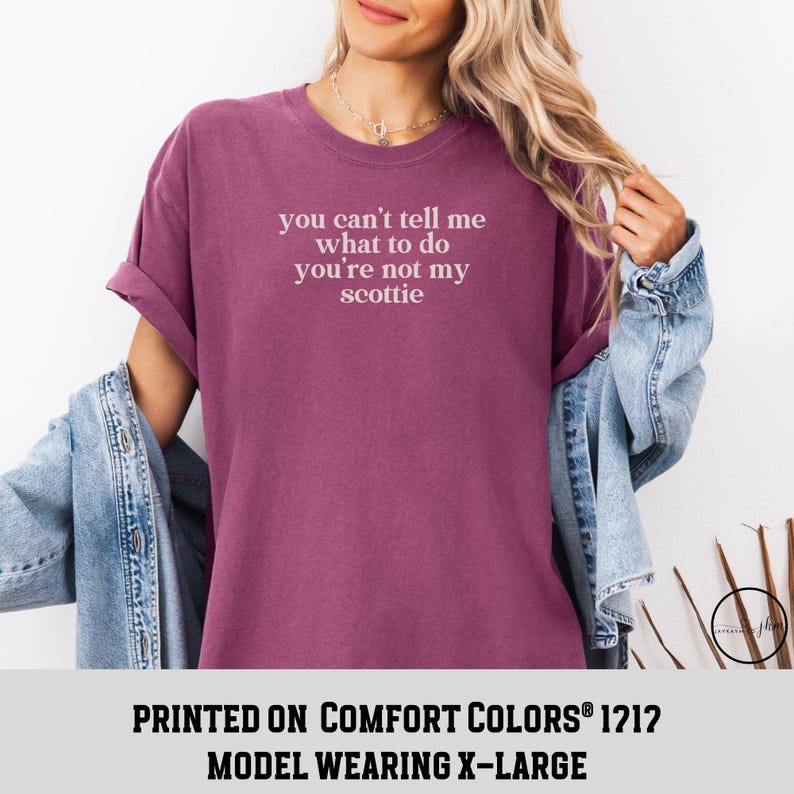 Puede incluir: Una camiseta granate con el texto blanco "you can't tell me what to do you're not my scottie". La camiseta es parte de una colecci&oacute;n de ropa. La modelo lleva una talla X-Large.