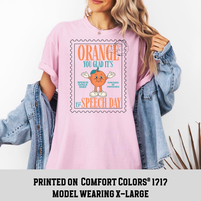 Puede incluir: Camiseta rosa claro con un dise&ntilde;o gr&aacute;fico de una naranja en un dise&ntilde;o de sello postal. El texto en la camiseta dice "ORANGE YOU GLAD IT'S SPEECH DAY". La camiseta es un modelo Comfort Colors 1212, talla X-Large.