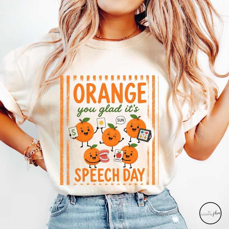Pu&ograve; includere: Una t-shirt color crema con una grafica di cinque arance disegnate con faccine. Il testo recita "ORANGE you glad it's SPEECH DAY". Le arance tengono in mano oggetti tra cui una carta con una S, una carta sole, un tablet, una dentiera e una carta mela.