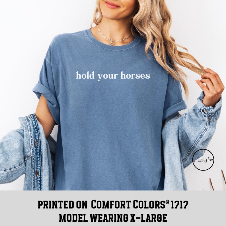 Op de afbeelding: Een blauw T-shirt met de tekst "hold your horses" in wit gedrukt op de voorkant. Het shirt is gemaakt van een zachte, comfortabele stof en perfect voor dagelijks gebruik.