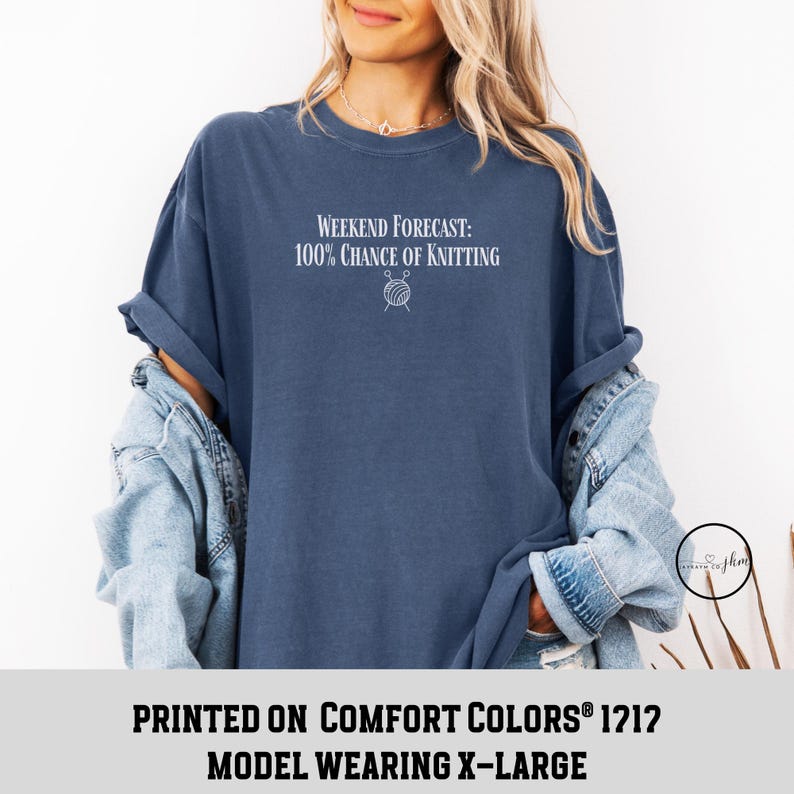 May include: A navy blue t-shirt with the text "WEEKEND FORECAST: 100% CHANCE OF KNITTING" and a small graphic of yarn and knitting needles. The model is wearing a size X-Large.