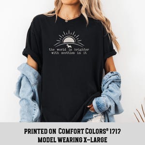May include: Black t-shirt featuring a graphic of a sun, a dog silhouette, and the text "the world is brighter with scotties in it." The shirt is printed on Comfort Colors 1212 material.