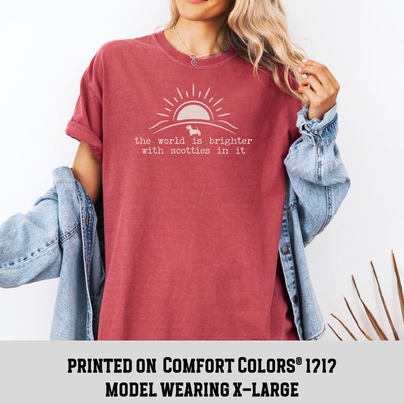 May include: A red-toned t-shirt with the text "the world is brighter with scotties in it" in a light color. The design includes a sun and a silhouette of a dog. The shirt is a Comfort Colors 1212 model.