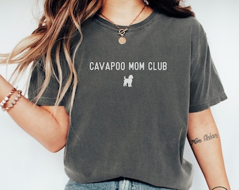 May include: Dark gray t-shirt with the text "CAVAPOO MOM CLUB" above a white Cavapoo dog illustration. The shirt is a comfortable, casual style.