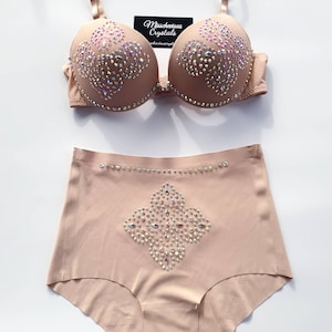 Op de afbeelding: Een huidkleurige lingerie set met een bh en een hoge taille slip. Beide delen zijn versierd met een geometrisch patroon van iriserende strass steentjes.