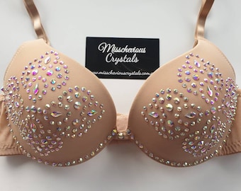 May include: A nude-colored bra with a crystal design. The bra is decorated with iridescent rhinestones in a heart shape. The bra is made of a soft, stretchy fabric. The bra is a size 34B. The bra is a great choice for a special occasion or a night out.