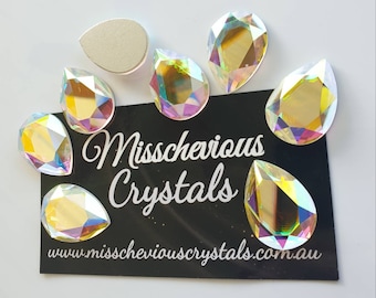 May include: Assortment of iridescent teardrop-shaped crystal rhinestones. The crystals are arranged on a black background with the text "Misschevious Crystals" and "www.misscheviouscrystals.com.au".