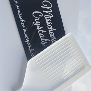 May include: White plastic diamond painting tray with a textured surface. The tray has a long, narrow handle and a wide, flat surface with ridges for holding diamonds.