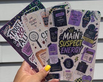 May include: Three rectangular sticker sheets featuring a dark, mystery-themed aesthetic with holographic glitter accents. The designs include text like 'Main Suspect Energy', 'Trust No One', and 'Evidence', alongside illustrations of typewriters, magnifying glasses, coffee cups, and books in shades of purple, black, and cream.