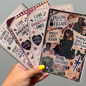 May include: A set of four rectangular holographic stickers featuring dark academia and autumn-themed illustrations. The designs include text such as Falling for the Villain, Morally Grey Season, Pumpkin Spice & Red Flags, and Fictional Men, Real Problems.