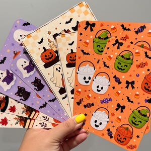 May include: A collection of rectangular bookmarks featuring various Halloween-themed patterns including ghosts, black cats, pumpkins, candy corn, and trick-or-treat buckets in orange, purple, and cream colors with bats and bows.