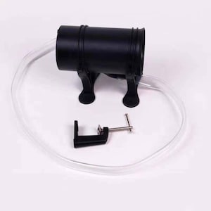 May include: A black plastic air pump with a clear plastic tube and a black clamp. The pump has two black legs and a round opening.