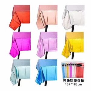 May include: A collection of colorful, metallic tablecloths in various shades, including red, pink, silver, purple, and gold. The tablecloths are displayed on black stands, showcasing their reflective surfaces. The image also includes a package of the tablecloths with the dimensions 137*183cm.