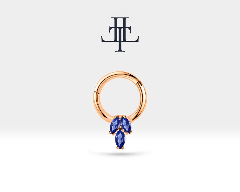 May include: A gold hoop earring with a cluster of three marquise shaped blue gemstones dangling from the bottom.