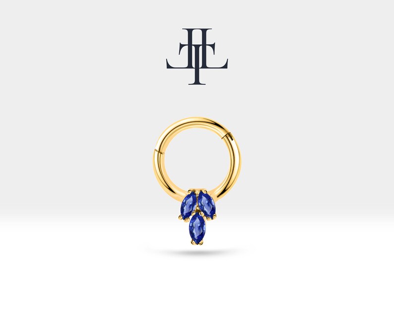 May include: A gold hoop earring with a dangling cluster of three marquise-shaped blue gemstones.