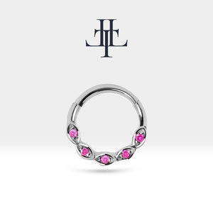 Op de afbeelding: Een zilveren clickerring met vijf roze edelstenen in een bladontwerp.