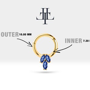 May include: A gold hoop earring with a cluster of three blue marquise shaped gemstones hanging from the bottom. The hoop is 10.00 mm outer diameter and 7.30 mm inner diameter. The text 'OUTER 10.00 MM' and 'INNER 7.30 MM' are written on the image.
