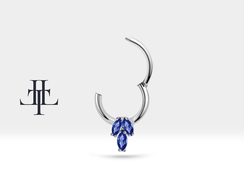 May include: A silver hoop earring with a cluster of three marquise shaped blue gemstones hanging from the bottom.