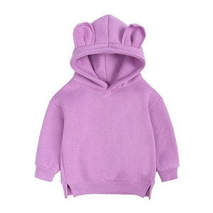 May include: A lavender-colored children's hoodie with a hood featuring bear ears. The long-sleeved sweatshirt has a kangaroo pocket and ribbed cuffs and hem. The hoodie is made of a soft, comfortable material.