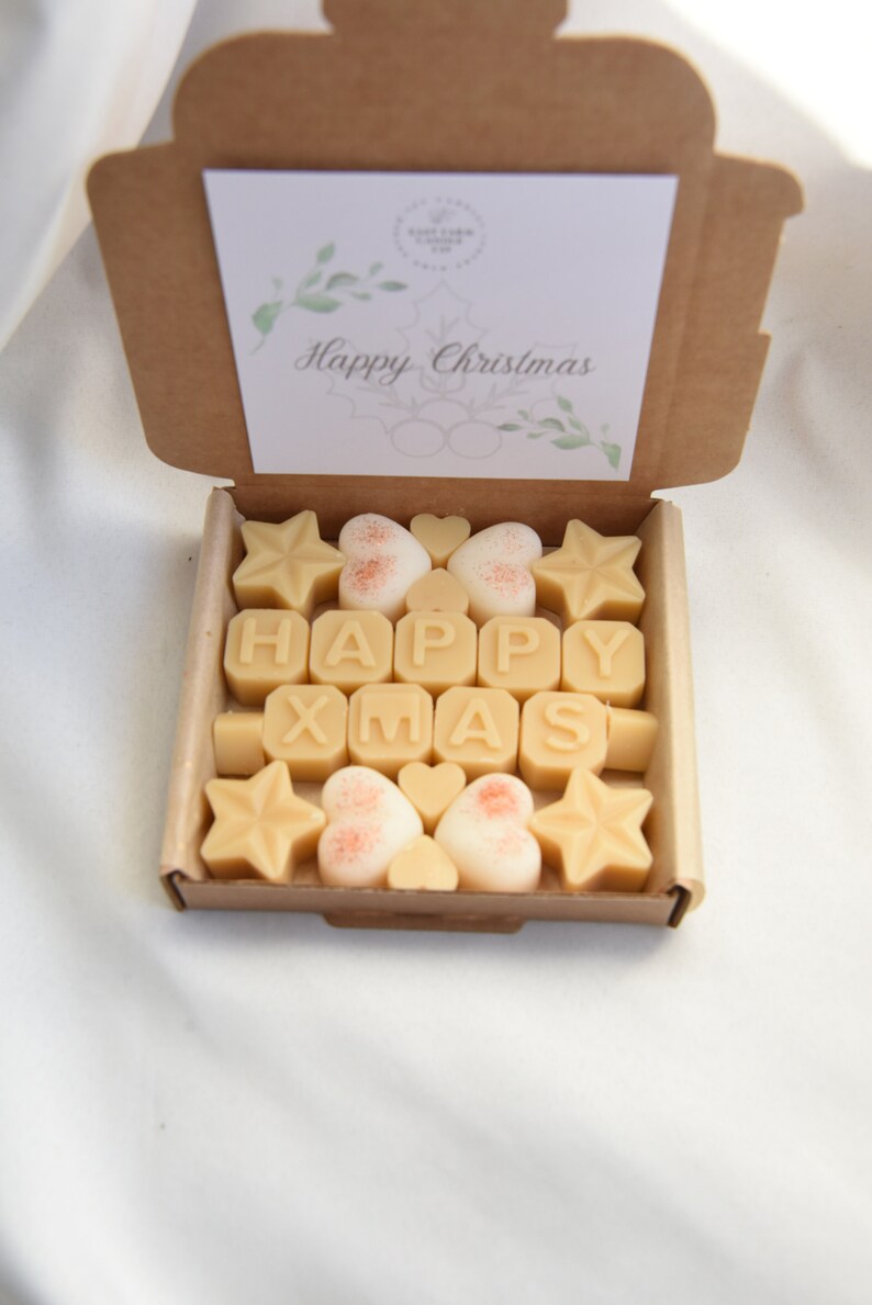 May include: A box of wax melts with a "Happy Christmas" card on top. The wax melts are shaped like stars, hearts, and letters that spell out "HAPPY XMAS".