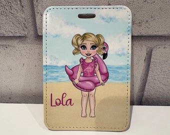Pode incluir: Uma etiqueta de bagagem retangular com uma menina de desenho animado com rabos de cavalo loiros e olhos azuis, usando um maiô rosa e um flutuador de flamingo. A etiqueta tem o nome "Lola" em script rosa, com um fundo de praia e céu.