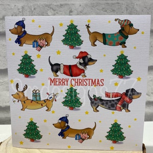 Pu&ograve; includere: Biglietto di Natale con illustrazioni di bassotti vestiti a festa. I cani indossano abiti da Babbo Natale, cappelli e sciarpe. Sono presenti anche alberi di Natale verdi, stelle gialle e la scritta "Merry Christmas".