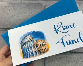 Pode incluir: Um cartão retangular branco com uma ilustração em aguarela do Coliseu de Roma sobre um fundo de céu azul e amarelo. O texto "Rome Fund" está impresso em letra cursiva azul à direita, acompanhado por um envelope azul brilhante.
