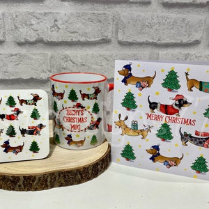 Pu&ograve; includere: Un set regalo a tema natalizio con tazza, sottobicchiere e biglietto d'auguri. Gli articoli presentano illustrazioni di bassotti in abiti festivi, alberi di Natale e le scritte "Becky's Christmas Mug" e "Merry Christmas". La tazza ha bordo e manico rossi.