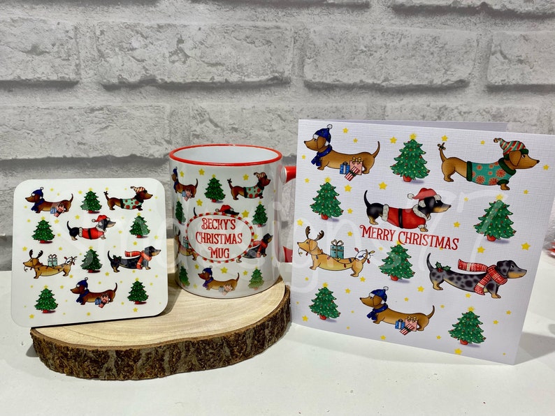 Pu&ograve; includere: Un set regalo a tema natalizio con tazza, sottobicchiere e biglietto d'auguri. Gli articoli presentano illustrazioni di bassotti in abiti festivi, alberi di Natale e le scritte "Becky's Christmas Mug" e "Merry Christmas". La tazza ha bordo e manico rossi.