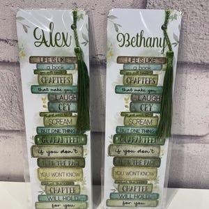 May include: Two personalized bookmarks with green tassels. Each bookmark features the name "Alex" or "Bethany" in script, with a quote about life and reading. The quote is arranged to look like a stack of books.