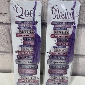 May include: Two personalized bookmarks with purple tassels. Each bookmark features a stack of books with the text "Life is like a book you will have chapters that make you laugh cry..." and a name at the top.