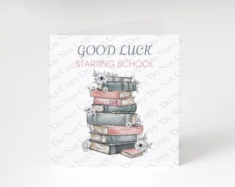 Pode incluir: Um cartão de felicitações com uma pilha de livros ilustrados em tons de rosa seco e verde-acinzentado. O texto GOOD LUCK STARTING SCHOOL está impresso em cinzento escuro e rosa. Pequenos detalhes florais desenhados à mão rodeiam os livros.