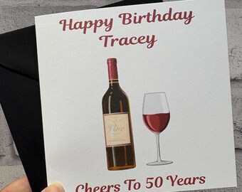 Pode incluir: Um cartão de felicitações quadrado com fundo branco apresentando uma garrafa de vinho tinto e uma taça de vinho tinto. O texto Happy Birthday Tracey está no topo e Cheers To 50 Years na parte inferior em letras vermelho-escuras.
